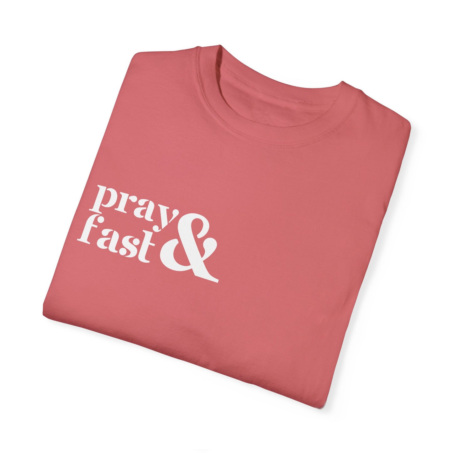 Folded coral colored relaxed t-shirt with "pray" written in white on top and "fast" written below in white with white ampersand next to both in top right chest area.